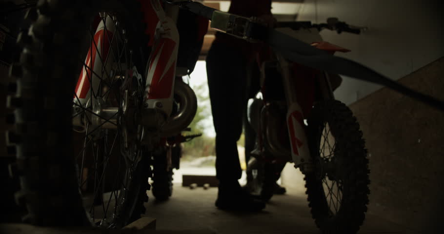 A closeup footage of a person driving back a dirty bike into a trailer after riding