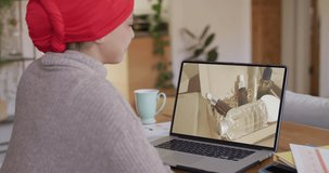 Biracial woman at table using laptop, shopping online for beauty products, slow motion. Retail business, sale, communication and digital interface digitally generated video.