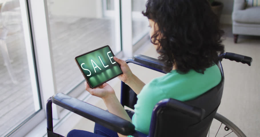 Biracial woman in wheelchair using tablet, online shopping during sale, slow motion. Retail business, sale, disability and digital interface digitally generated video.