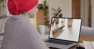 Biracial woman at table using laptop, online shopping for beauty products, slow motion. Retail business, sale, communication and digital interface digitally generated video.
