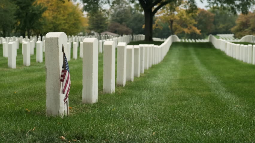 Field of American flags at Sunset. Flags on grave stones for memorial day remembrance at a cemetery. Small American flags and headstones at National cemetary- Memorial Day display.