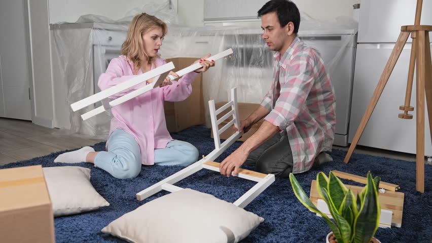 Love couple assembly new home ikea furniture. Family moving into house. Joyful guy buy hand made chair. Girl sit floor. People do kitchen renovation. Man rent flat. Team work craft diy. Manual repair. Royalty-Free Stock Footage #1110034851