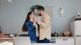 Young joyful couple celebrates Christmas Eve by dancing in festively decorated kitchen. Embracing the holiday spirit, lively moves encapsulate essence of family festivities and winter celebrations. - Powered by Shutterstock - Get 15% off with code: PIKWIZARD15