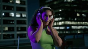 Portrait of gorgeous beautiful queen woman enjoying summer night in downtown. Joyful diverse model girl in trendy outfit wearing headphones dancing into music under street lights in night illumination - Powered by Shutterstock - Get 15% off with code: PIKWIZARD15