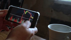 Man checks stock market chart on his mobile phone at home.  business and finance concept High quality video. Black background screen. 