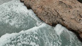 Aerial view waves crash on the rocks. Turquoise colored water. Slow motion 4K
