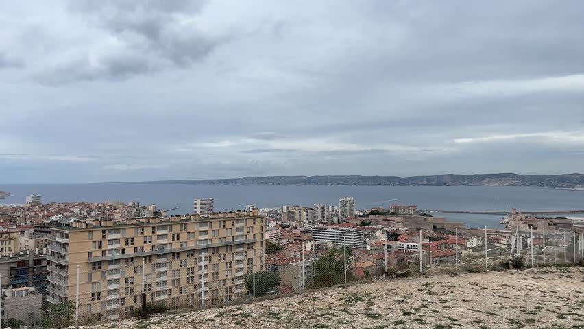 The coast of France and Marseille with apartment buildings and a fence in the foreground