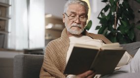 Portrait of gray haired senior man under the blanket reading book literature at cozy home Calm relaxed mature male with glasses enjoying weekend leisure time alone indoors - Powered by Shutterstock - Get 15% off with code: PIKWIZARD15
