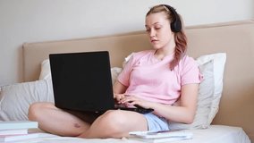 Close-up of a teenage girl using a laptop while sitting on the bed