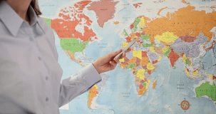 World map pointer in hand of accountant outlines borders of different countries. Teacher shows students countries of world via video conference
