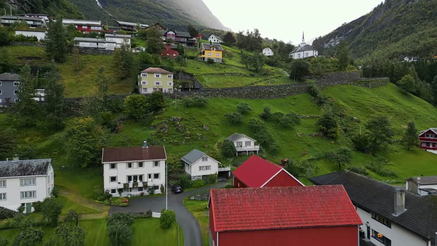 Aerial over the lush green hills with typical housing of Gieranger, Norway. Drone dolly forward shot