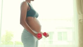 Beautiful african american mother pregnant healthy taking care of her health by play sports exercising in the bedroom lifting dumbbells up and down slowly to flex her arm muscles before giving birth. - Powered by Shutterstock - Get 15% off with code: PIKWIZARD15