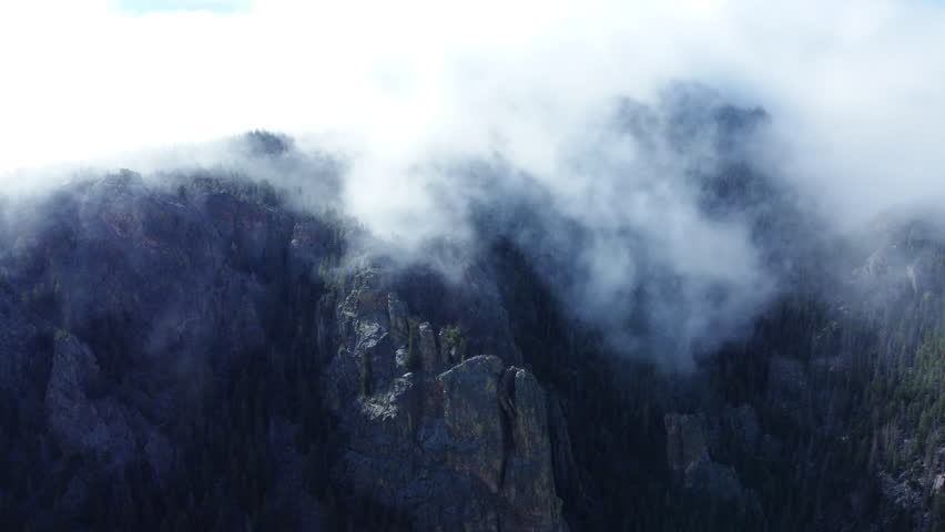 Cloud cover rolls over the Colorado mountains into the valley below