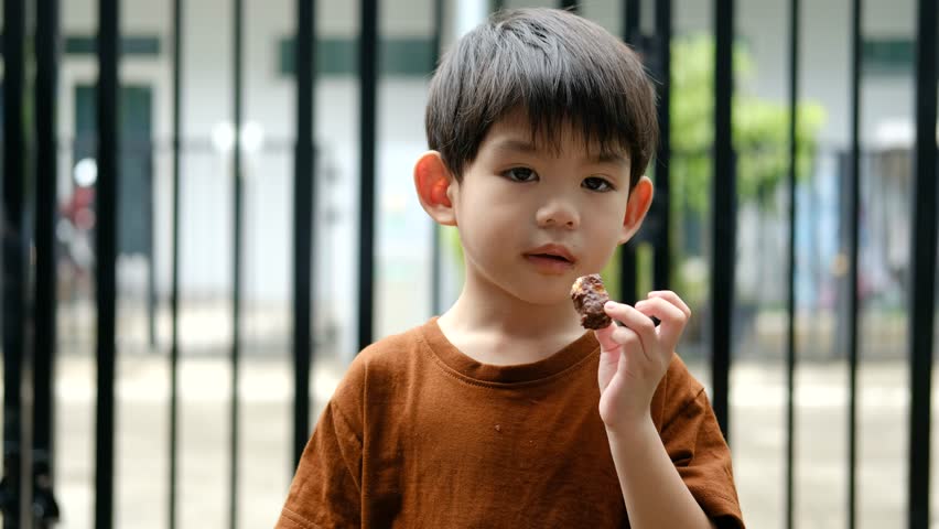 Happy face of Asian boy eating chocolate candy
