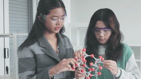 Asian female schoolgirl studying Scientist examining molecular model in science classroom - Powered by Shutterstock - Get 15% off with code: PIKWIZARD15