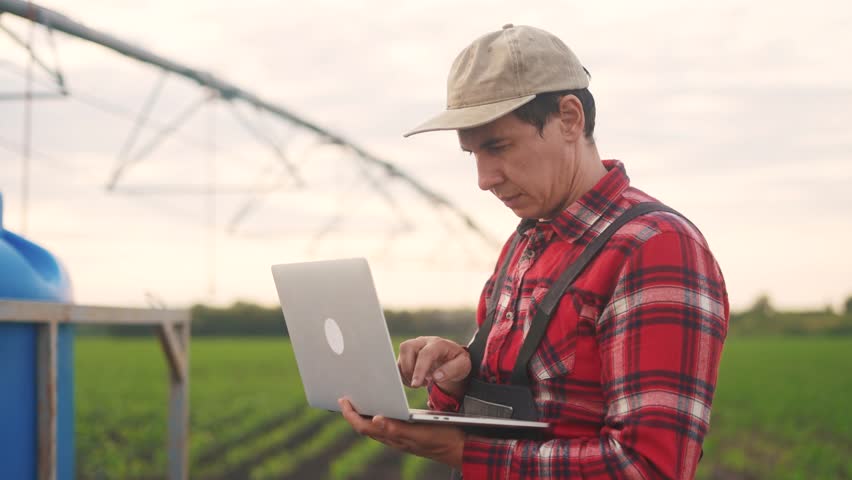 irrigation agriculture. a male farmer works on a laptop in a field with corn. irrigation agriculture business concept. lifestyle farmer scientist studying corn . healthy natural foods concept Royalty-Free Stock Footage #1110066075