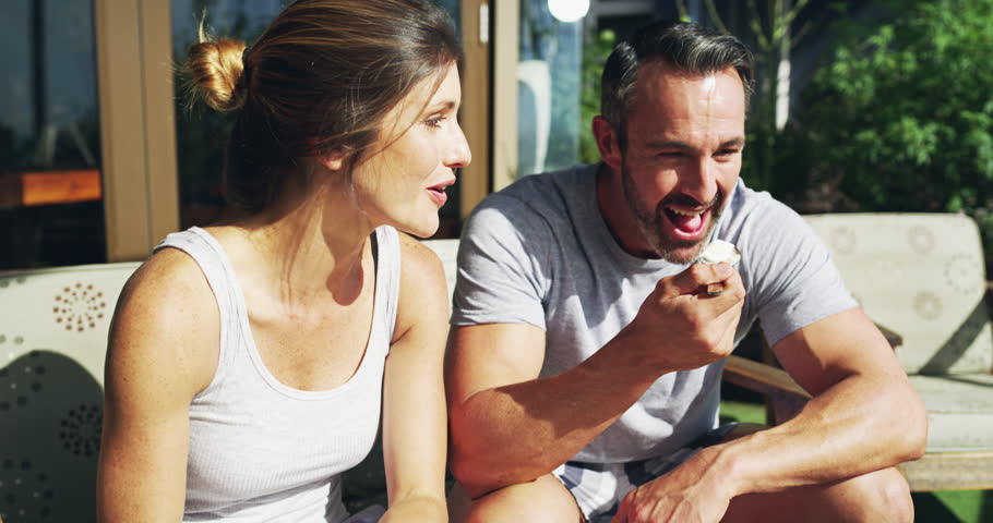 Couple, talking and happy for breakfast on garden patio with love, care or diet with bonding, relax or morning sunshine. Man, woman and eating food on date, health or vacation with chat in backyard
