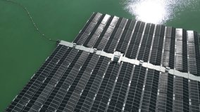 Zoom out of a floating solar farm with many solar panels on a lake