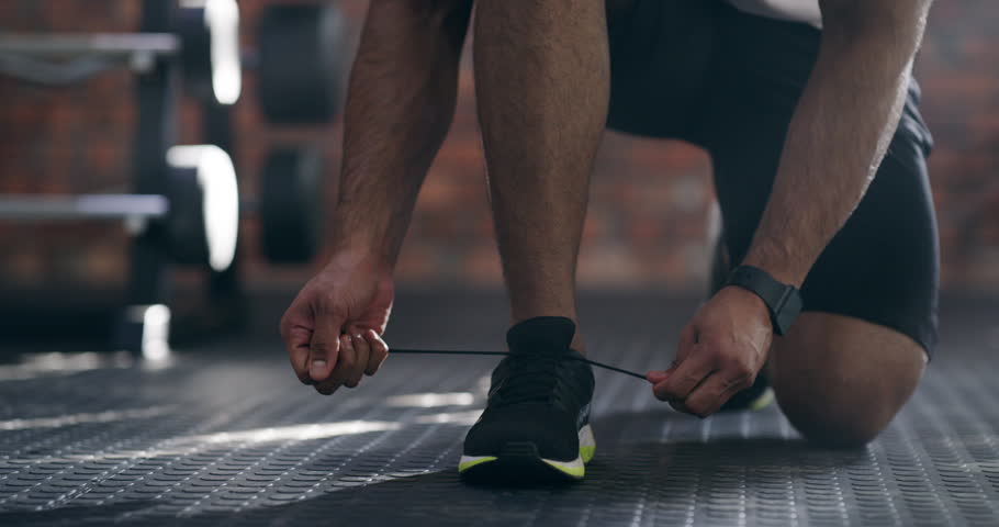 Feet, tie or shoes for workout, fitness or exercise with determination and getting ready at gymnasium. Person, man or athlete tying laces with sportswear and resilience for physical activity or body Royalty-Free Stock Footage #1110083315