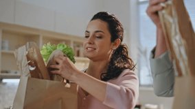 Closeup family taking purchased products on kitchen countertop from paper bags. Happy cheerful couple unpacking ecological supermarket packages with healthy food. Spouses sorting shoppings together. - Powered by Shutterstock - Get 15% off with code: PIKWIZARD15
