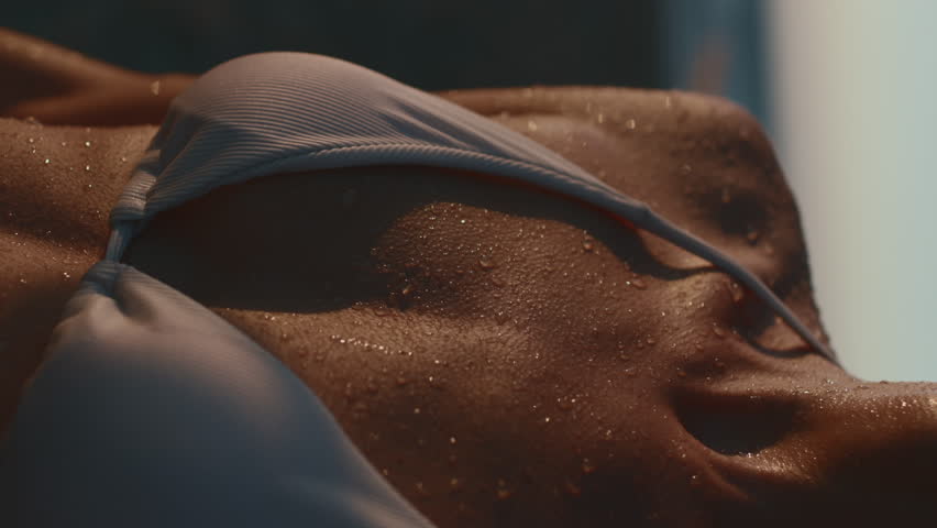 vertical shot. drops of water on the body of a tanned and young woman at sunset. close-up. holiday at sea. natural outdoor lifestyle. Camping. relaxation on the beach.