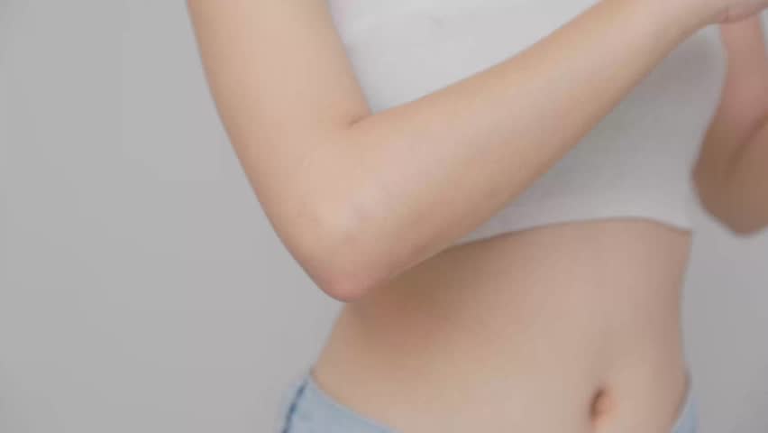 Asian young woman apply cream or lotion on her elbow for protect dry skin for moisturizing on skin on her elbow gently.