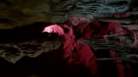 Abstract limestone cave background. Close-up view of old cave with stalagmites and changing illumination from red and magenta to blue. Slow motion vertical video. Soft focus. Speleology theme.
