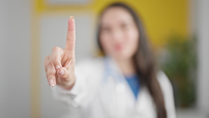 Young beautiful hispanic woman doctor saying no with finger at the clinic Royalty-Free Stock Footage #1110093547