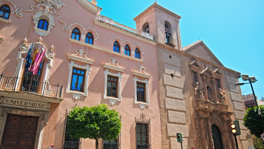 Beautiful colourful University building in the city of Murcia. Universidad de Murcia: Facultad de Derecho with Spanish and European flags attached in Spain, Europe.