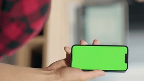 Close Up of Phone with Green Screen Mock Up Display In Male Hands. Man Sitting In Office Browsing Internet , Watching Content, News, Financial Reports on Phone