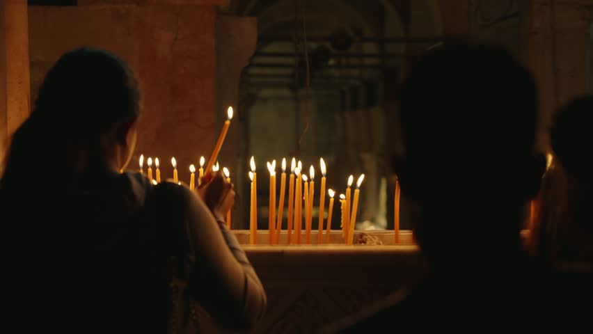 People light candles in Church of the Holy Sepulchre in Old City of Jerusalem. Famous and holy church for Christianity in ancient city of Jerusalem. Visitors put candles before prayer