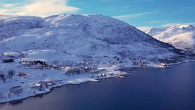 Snow covered mountain range on coastline in winter, Norway. Surroundings of town Tromso. Panoramic aerial view landscape of nordic snow cowered mountains, houses and ocean. Troms county, Fjordgard - Powered by Shutterstock - Get 15% off with code: PIKWIZARD15