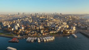 At sunset, the drone takes video over the sea, away from the Galata Tower. Aerial view of sea and land traffic. Istanbul, Turkey.