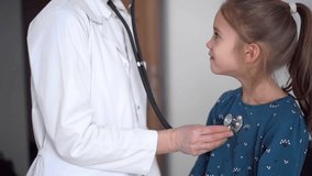 Doctor and patient in the clinic. Pediatrician is examining a little fair-haired girl with a stethoscope. Medicine, healthcare concepts