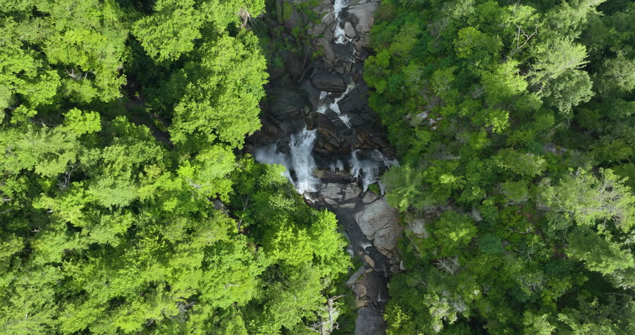 Whitewater Falls with falling down clear water from rocky boulders between green lush woods in Nantahala National Forest, North Carolina, USA