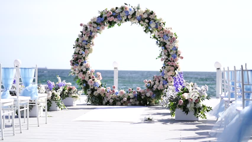 A wedding ceremony with the sea as a backdrop. Wedding arch decorated with fresh flowers. Royalty-Free Stock Footage #1110118211