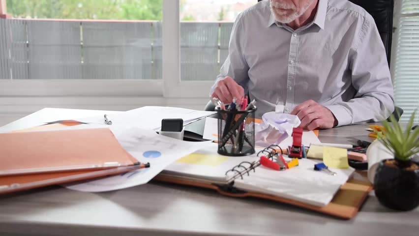 Disorganized businessman working and looking for something on a messy desk at office