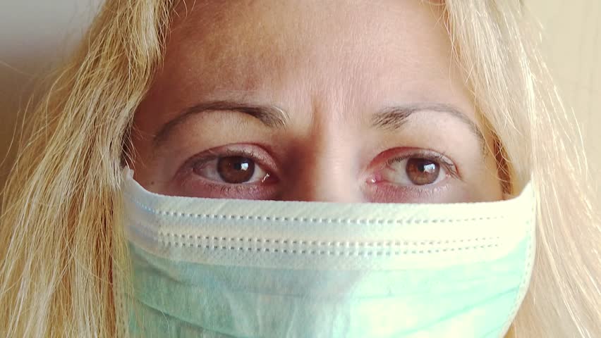front view closeup of a blonde girl with a sanitary mask on white background isolated. Concept of the epidemic outbreak, quarantine for public health care and outbreak of the corona-virus. SLOW MOTION Royalty-Free Stock Footage #1110120693