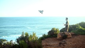 Beach, technology and a man flying a drone over the ocean in nature for video footage during summer. Sky, sea and horizon with a person using a remote to control aircraft on the coast by the sea