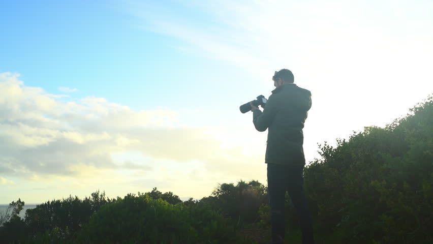 Outdoor, man and photographer with a view, camera and lens flare with ocean, capture moment or travel. Professional, guy or person with water, sky mockup or tourism with nature adventure photography