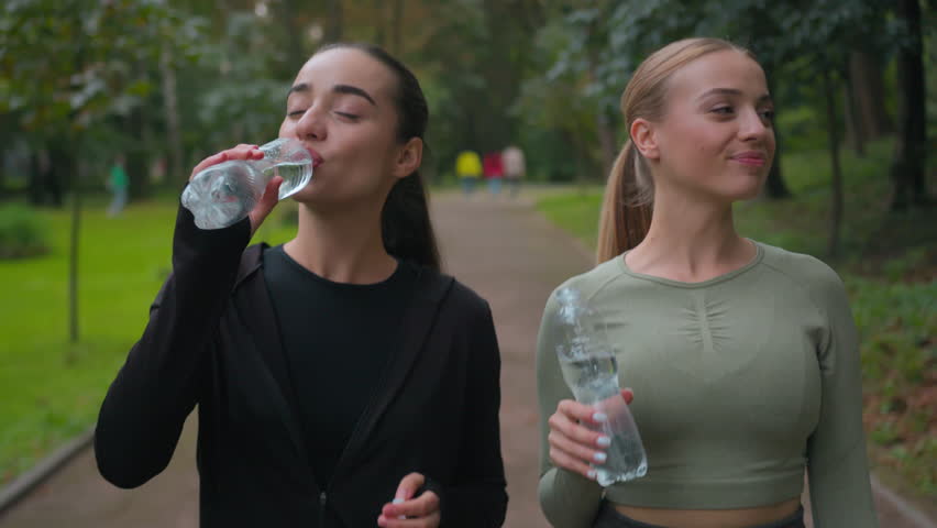 mujer joven fitness en ropa deportiva bebiendo agua después de