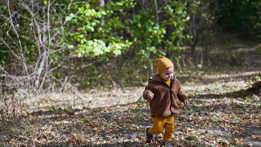 Caucasian kid running in the autumn park. Lovely baby boy having good time in nature on sunny day.