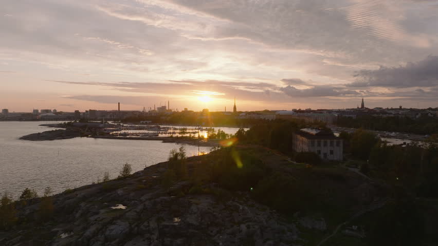 Romantic view of coast and city silhouette against color sunset sky. Forwards fly above islands and marina. Helsinki, Finland