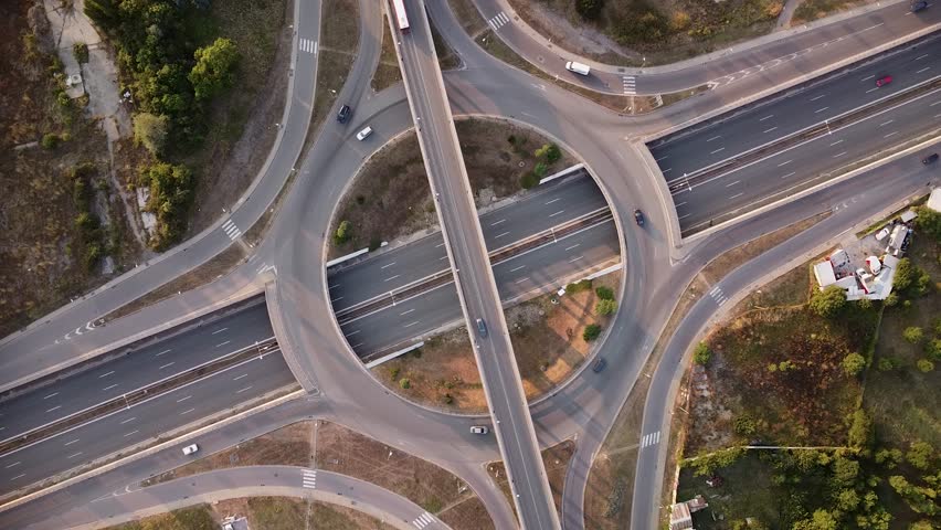 Aerial drone footage of a freeway intersection. Multi level intersection in Europe filmed from above. Multi-level junction road with moving cars at sunset. Royalty-Free Stock Footage #1110129467
