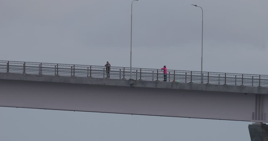 Seniors fishing from bridge on moody day, static view from below