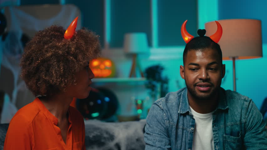 Happy African American woman and man with devil horns celebrating Halloween, fun
