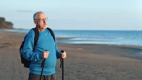 Relaxed grandfather with Scandinavian walking stick and backpack enjoy sunset natural light at sea beach closeup. Smiling elderly man relax admiring nature seascape retirement sport physical activity  - Powered by Shutterstock - Get 15% off with code: PIKWIZARD15