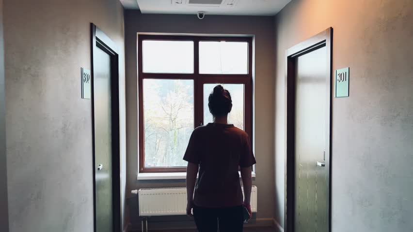 a girl comes to the window and looks at the beautiful landscape of mountain ranges and the Olympic village