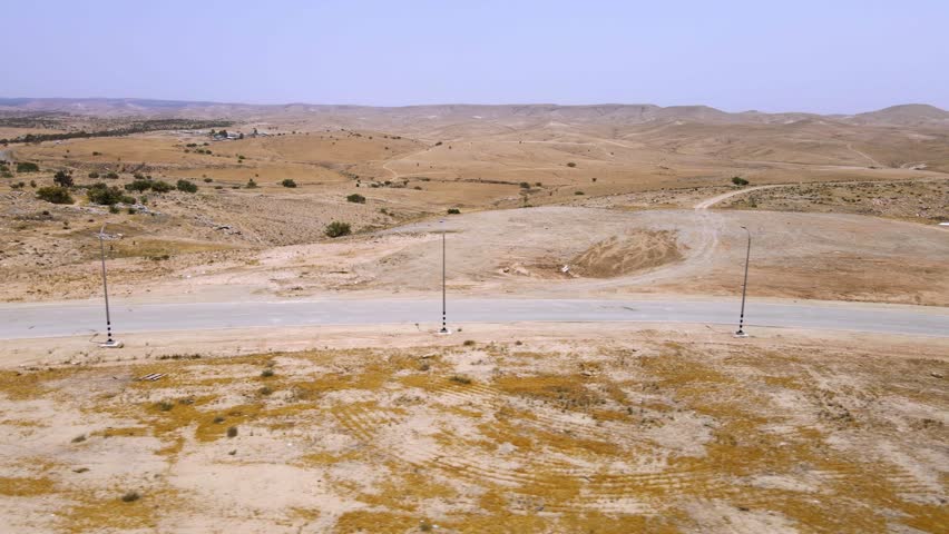A road in the middle of the desert in the Negev, southern Israel Brown hills blue sky.
Ariel Dron Shot.