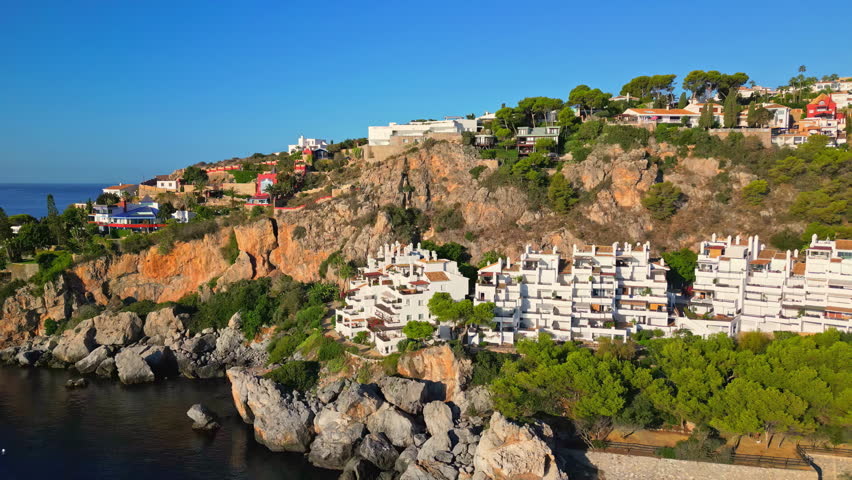 Aerial drone forward moving shot flying over a beautiful resort along rocky beach in Playa Marina del Este, Almunecar, Granada, Spain